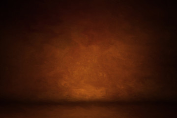 Photo background is orange red. textured wall rolling in the floor. studio photography background illuminated by the directed light. Traditional painted canvas or muslin fabric cloth studio backdrop