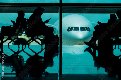 Silhouette of many Passengers Waiting for Boarding in Departure Terminal in the Airport. Airplane as background photo