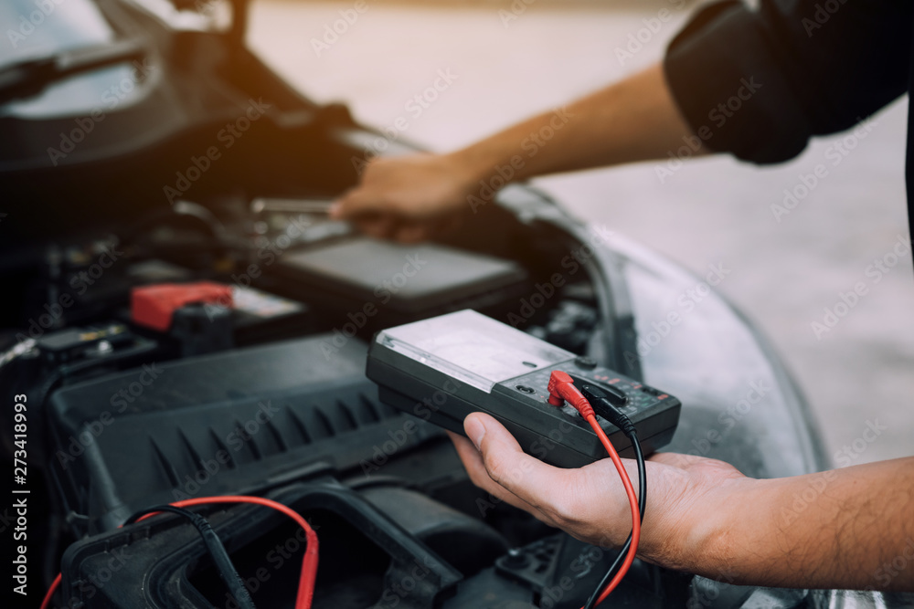 Obraz premium The car mechanic is carrying a battery meter and checking the general condition of the engine.
