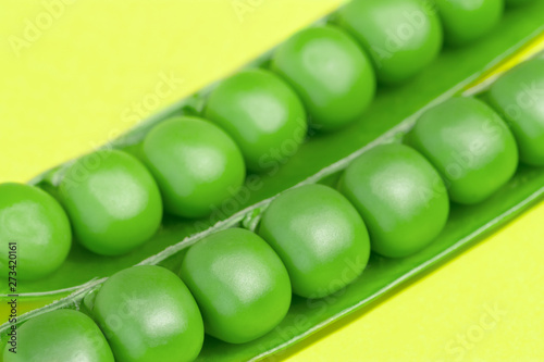 Fresh green pea pods and peas on the yellow background.