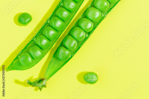 Fresh green pea pods and peas on the yellow background.