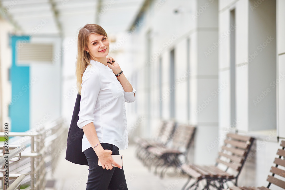 business woman smiling at the camera and holding a phone in her hands. business woman smiling at the camera and holding a phone in her hands.
