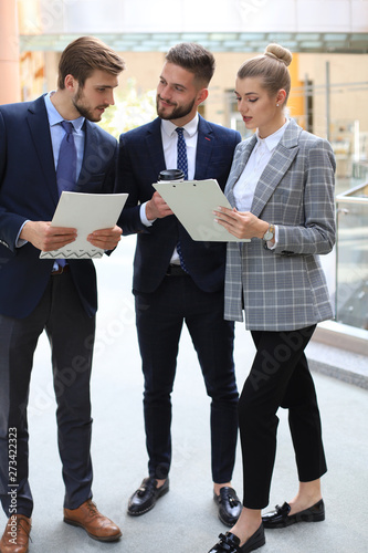 Three young businessmen standing discussing business at an office meeting.