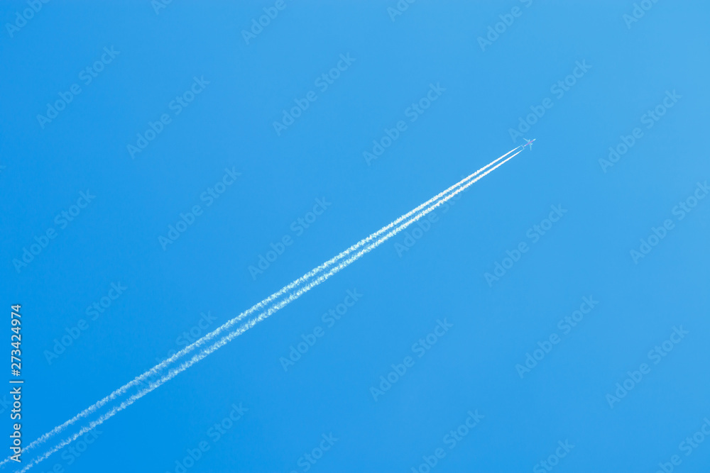 jet airplane flying at high altitude with contrails on beautiful blue sky, contrails or condensation trails or vapour trails, line-shaped clouds produced by aircraft engine exhaust - obrazy, fototapety, plakaty 