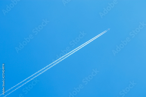 jet airplane flying at high altitude with contrails on beautiful blue sky, contrails or condensation trails or vapour trails, line-shaped clouds produced by aircraft engine exhaust photo