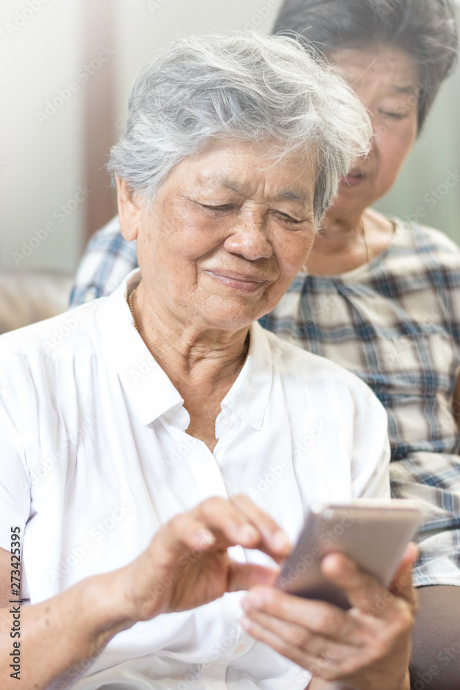 Happy elderly senior people society lifestyle technology concept. Ageing Asia women using tablet smartphone or mobile phone share social media together in wellbeing county home. Happy elderly senior people society lifestyle technology concept. Ageing Asia women using tablet smartphone or mobile phone share social media together in wellbeing county home.