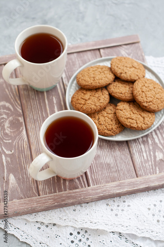 A tasty snack: two cups of tea and a plate of cookies. © myrka
