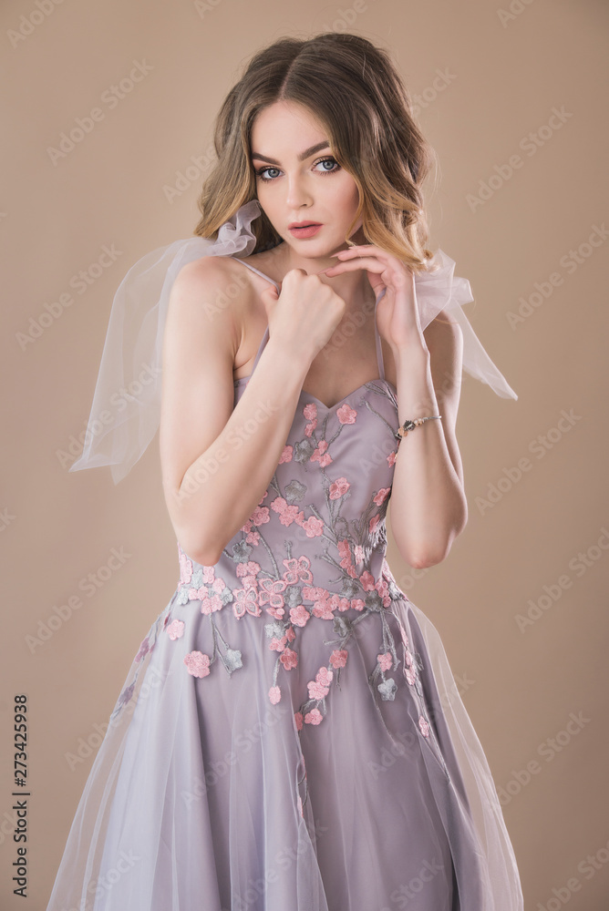 Pretty female model portrait in elegant dress on beige background Pretty female model portrait in elegant dress on beige background