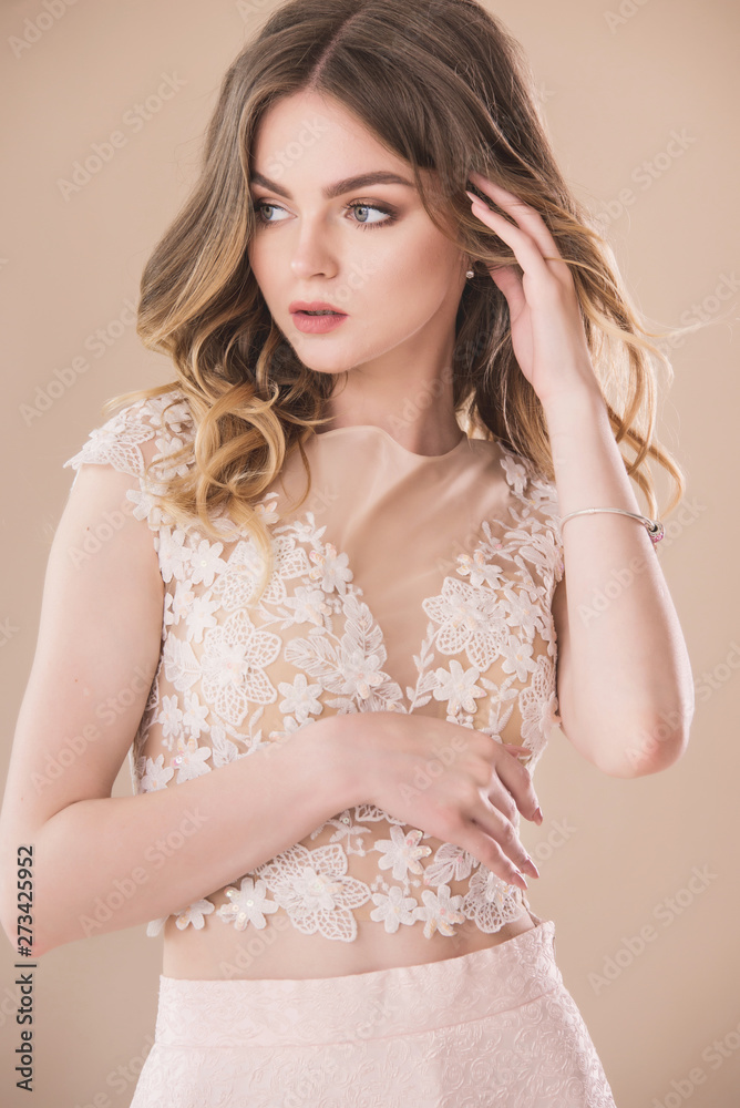 Pretty female model portrait in elegant dress on beige background Pretty female model portrait in elegant dress on beige background