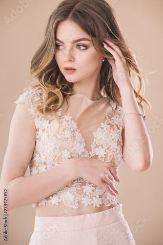 Pretty female model portrait in elegant dress on beige background