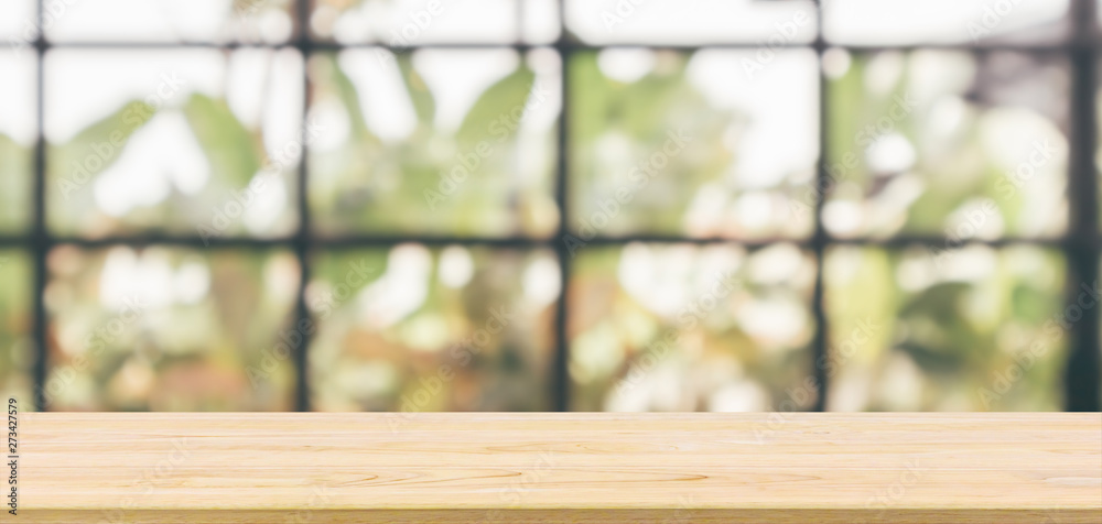 Empty wooden table top with cafe restaurant or coffee shop window interior abstract blur defocused with bokeh light background for montage product display