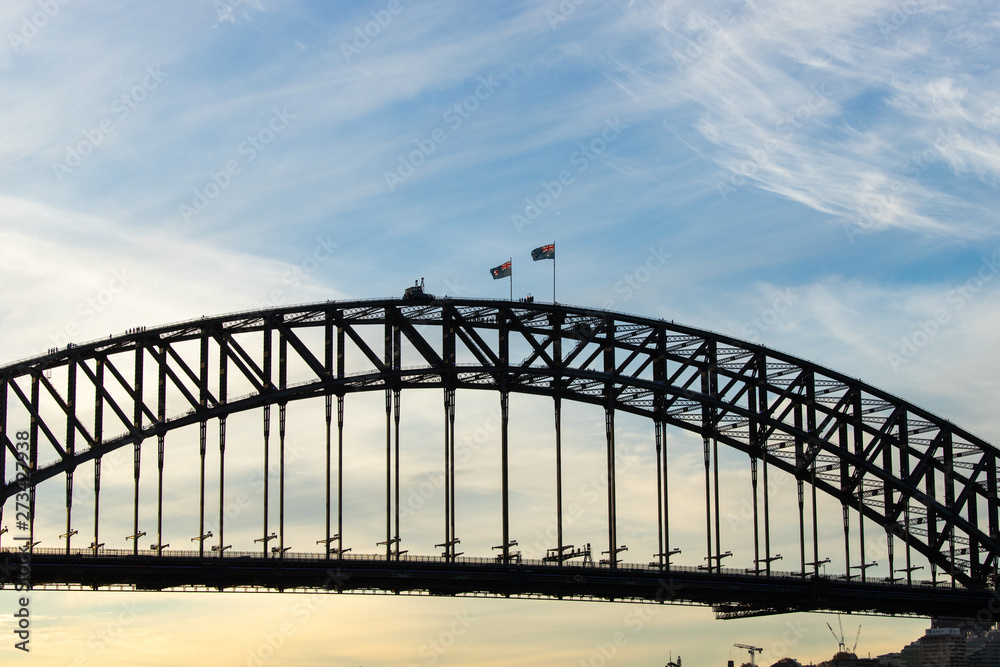 Australian flag above Sydney Harbour Bridge with afternoon sky.