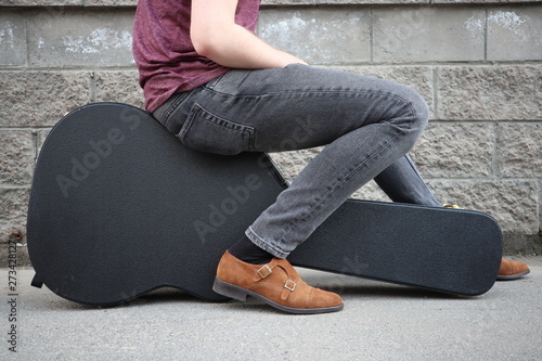 man sitting on a black guitar case. hard case for electric guitar