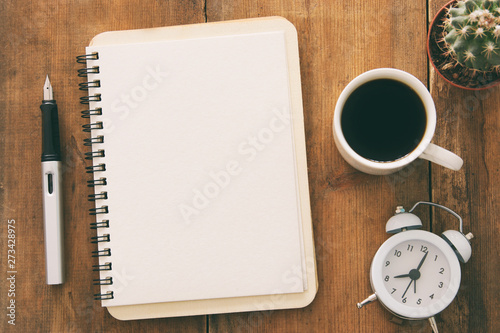 Open notebook with empty pages and other office supplies over wooden old office desk table. Top view, flat lay © tomertu