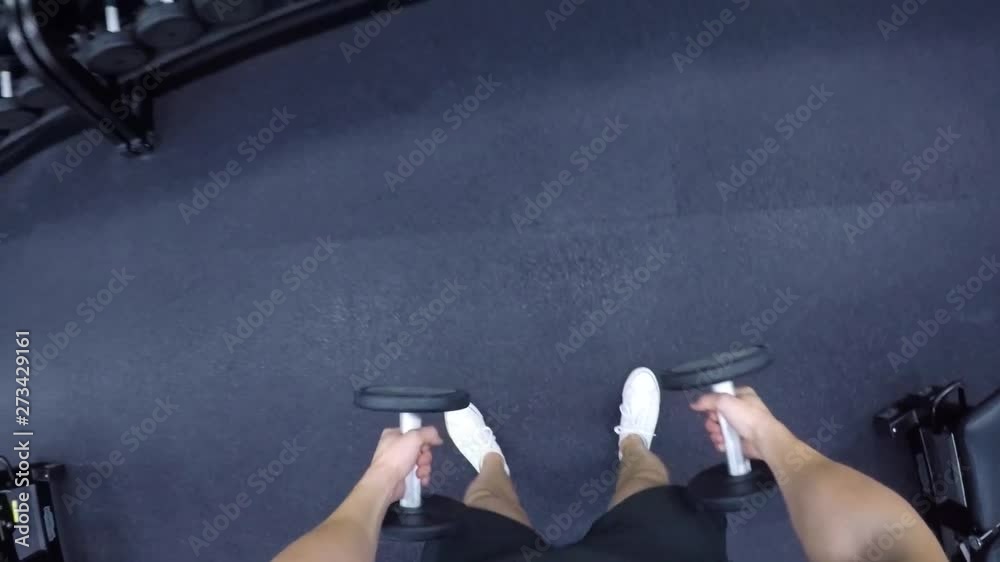 POV man trains biceps performing curls with dumbbells at a gym
