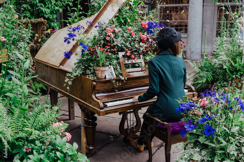 Woman playing piano decorated with flowers at Covent Garden, London. Rear view. photo