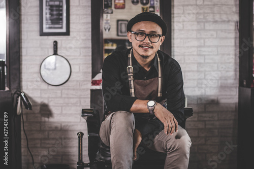 portrait of stylist barber sitting at barbershop chair