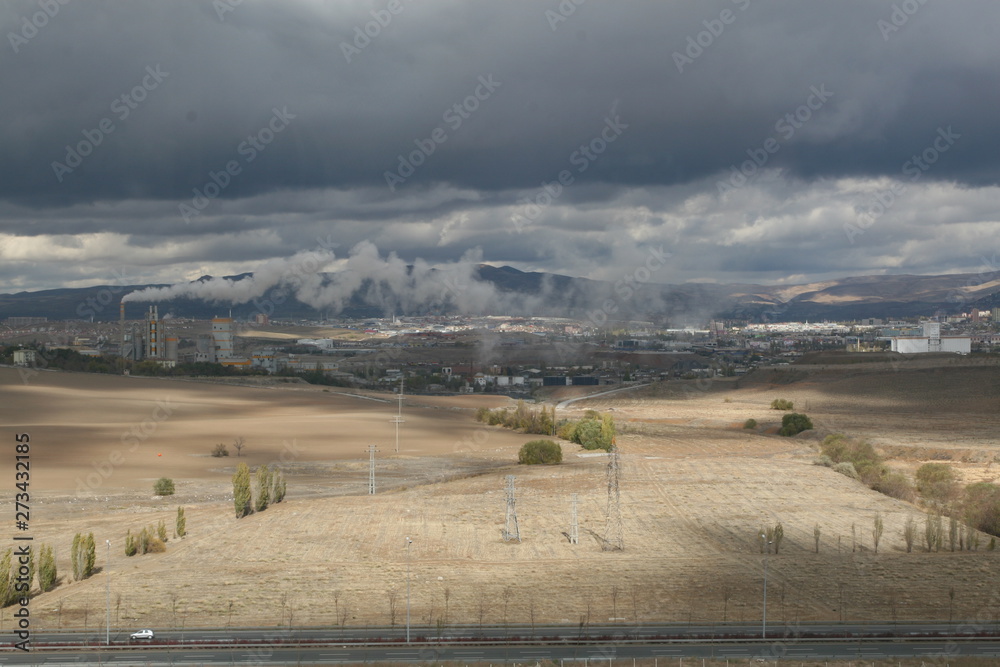 Obraz premium Air pollution created by the smoke coming from the chimney of the cement factory in Turkey's capital city Ankara, cities, mountains and clouds.
