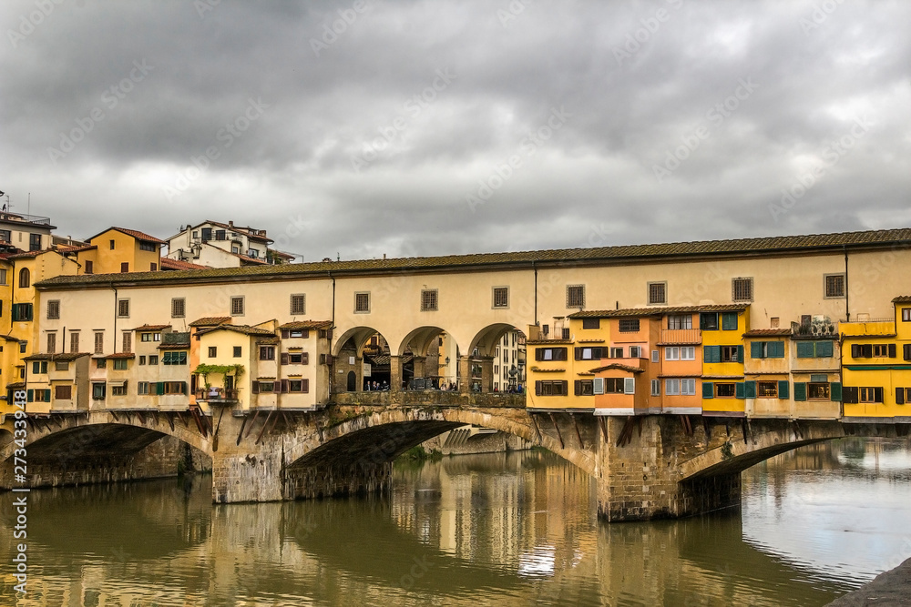 Italy, Florence, the capital of Tuscany. View of the famous Ponte Vecchio bridge over the Arno River. Pre-storm May sky.