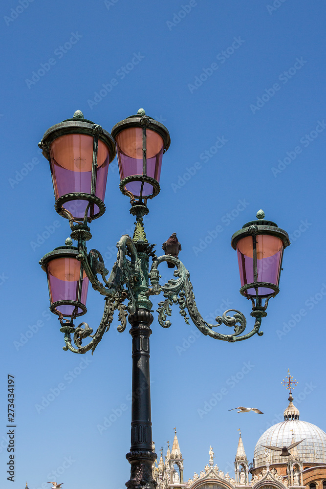 Italy, Venice. Street bronze lamp on the background of one of the facades of the Cathedral of St. Mark. Pigeons and seagulls.