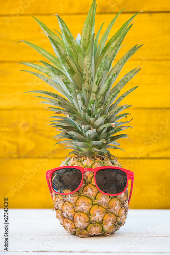 Holiday pineapple have sunglasses on yellow wooden background
