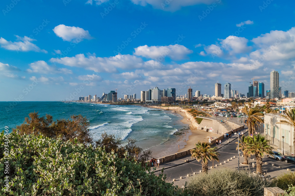 Panoramic view of modern Tel Aviv sky line and beach on sunny day. Mediterranean sea, Israel. Sea waves and cloudy sky.