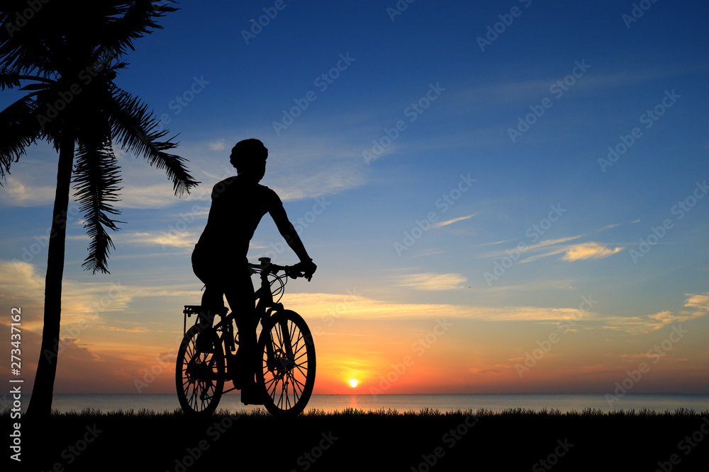 Fototapeta premium Silhouette man and bike relaxing on blurry sunrise sky background.