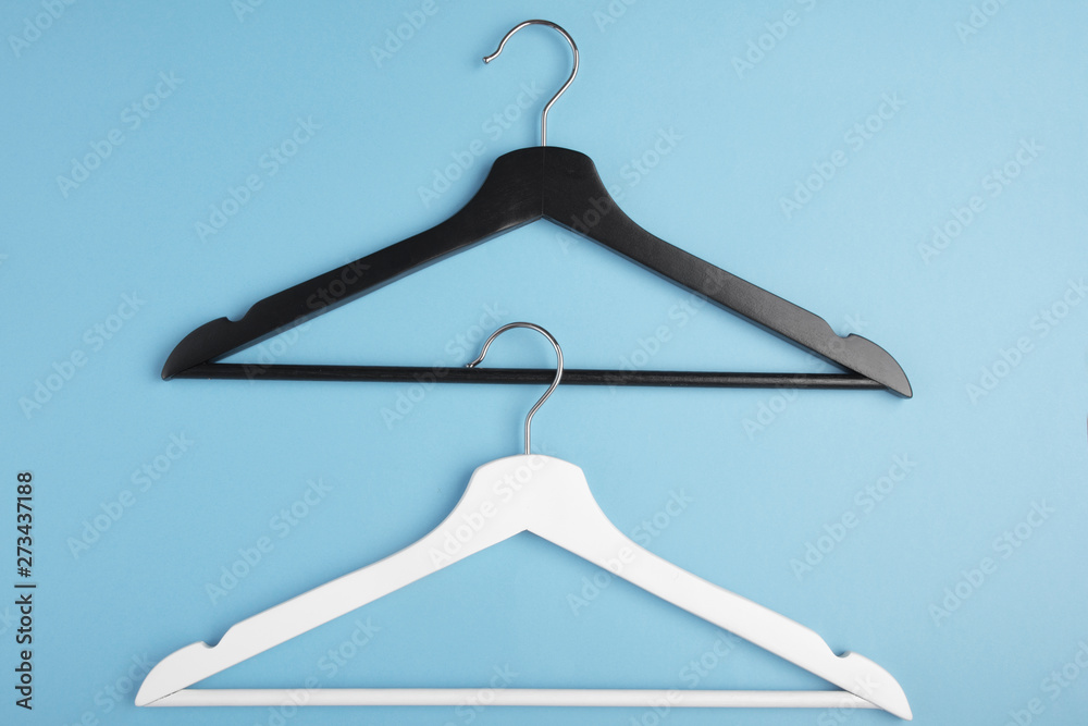Black and white hangers interlocked with each other on blue background. Concept view.