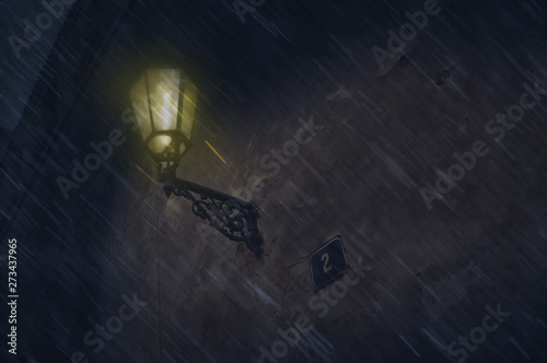 Antique streetlight lamp on an ancient stone wall in the rain late at night