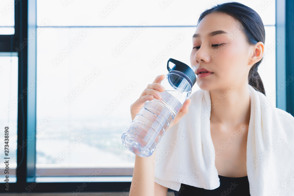 asian healthy aport woman relaxing in gym after workout hand hold pure water drink and white towel asian healthy aport woman relaxing in gym after workout hand hold pure water drink and white towel