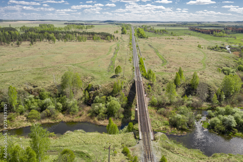 Aerial view; drone flying over the old railway bridge crossing the river; dense vegetation on the banks of the river; beautiful picturesque road; transportation through the landmarks