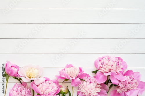Pink peonies on wooden background. Copy space, top view.