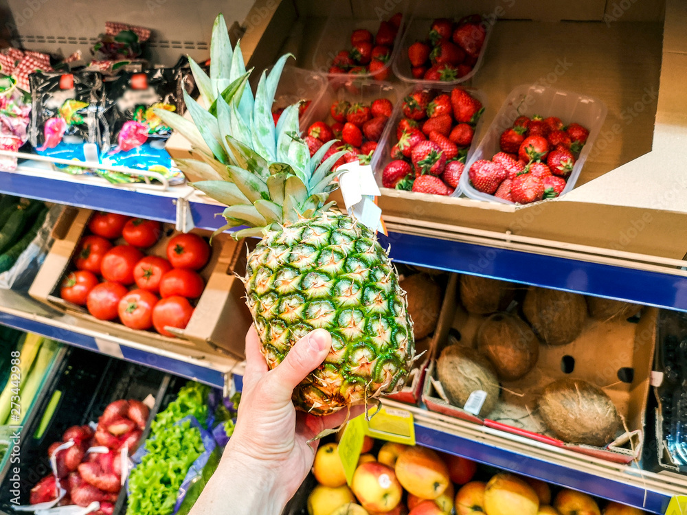 Man choosing pineapple during shopping at the supermarket. Man picking up, choosing fruits, pineapples Man choosing pineapple during shopping at the supermarket. Man picking up, choosing fruits, pineapples