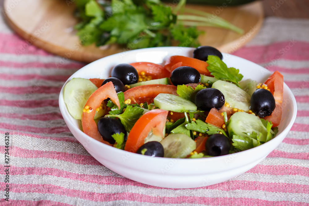 Vegetarian salad of tomatoes, cucumbers, parsley, olives and mustard on linen tablecloth. Vegetarian salad of tomatoes, cucumbers, parsley, olives and mustard on linen tablecloth.