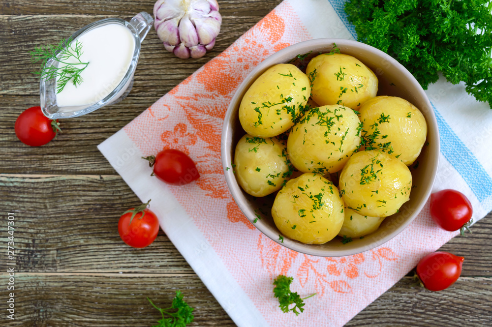 Tasty boiled young potatoes with butter and dill in a bowl on a wooden table. Top view, flat lay. Tasty boiled young potatoes with butter and dill in a bowl on a wooden table. Top view, flat lay.