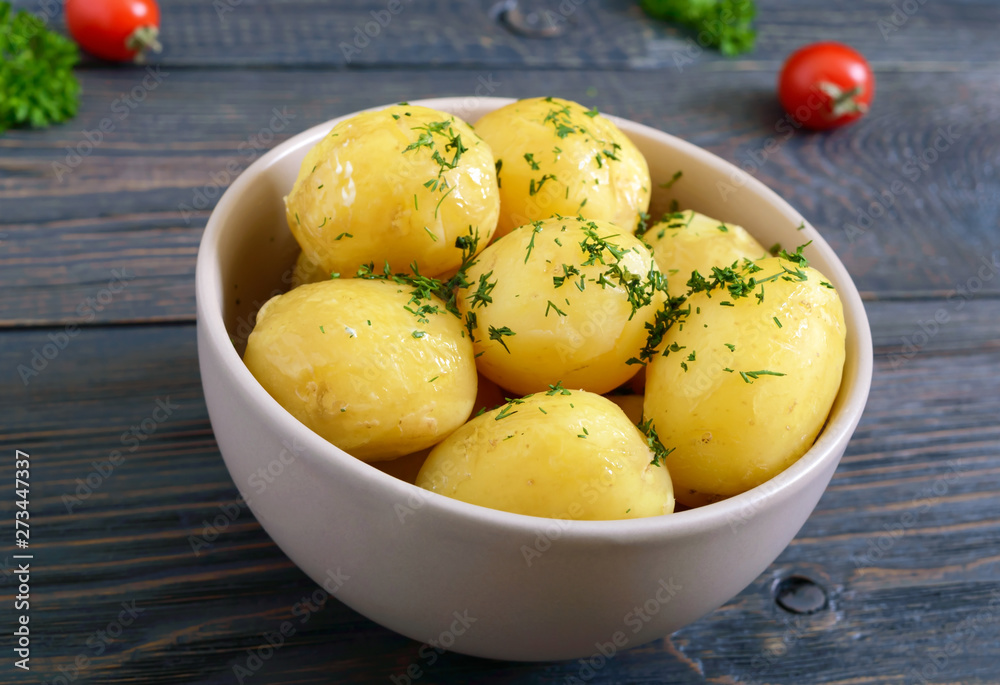 Tasty boiled young potatoes with butter and dill in a bowl on a dark background. Tasty boiled young potatoes with butter and dill in a bowl on a dark background.