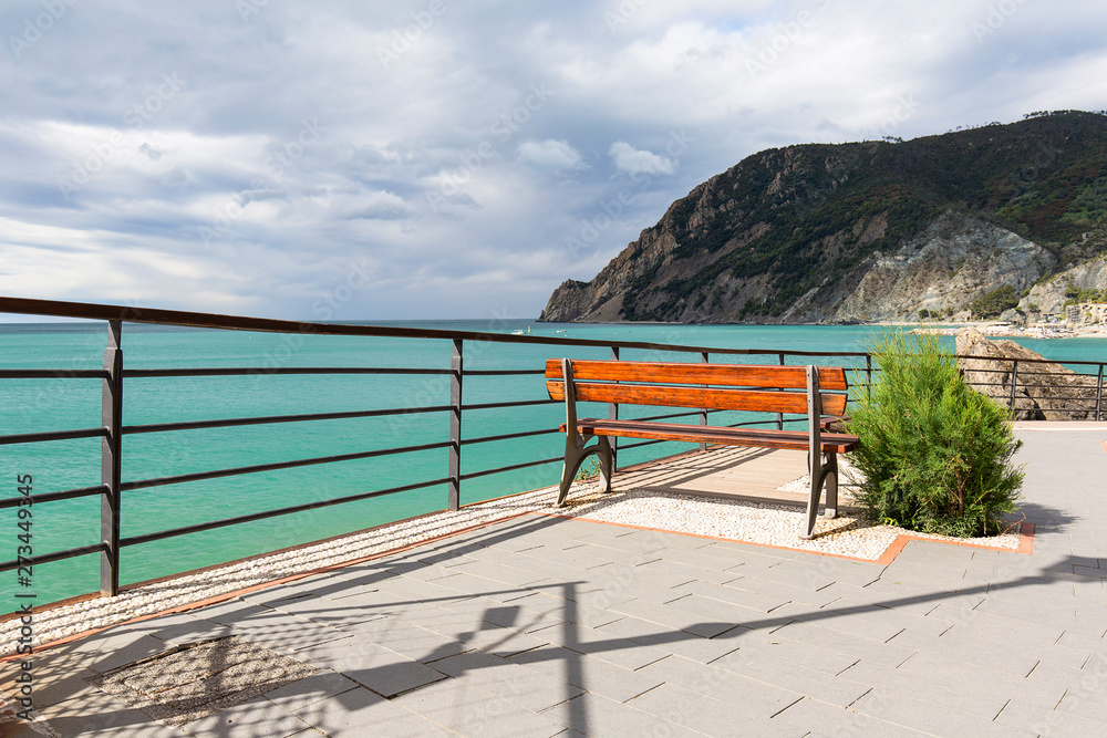 An empty wooden bench with a view of the Mediterranean Sea on seaside promenade, Cinque Terre, Monterosso, Italy