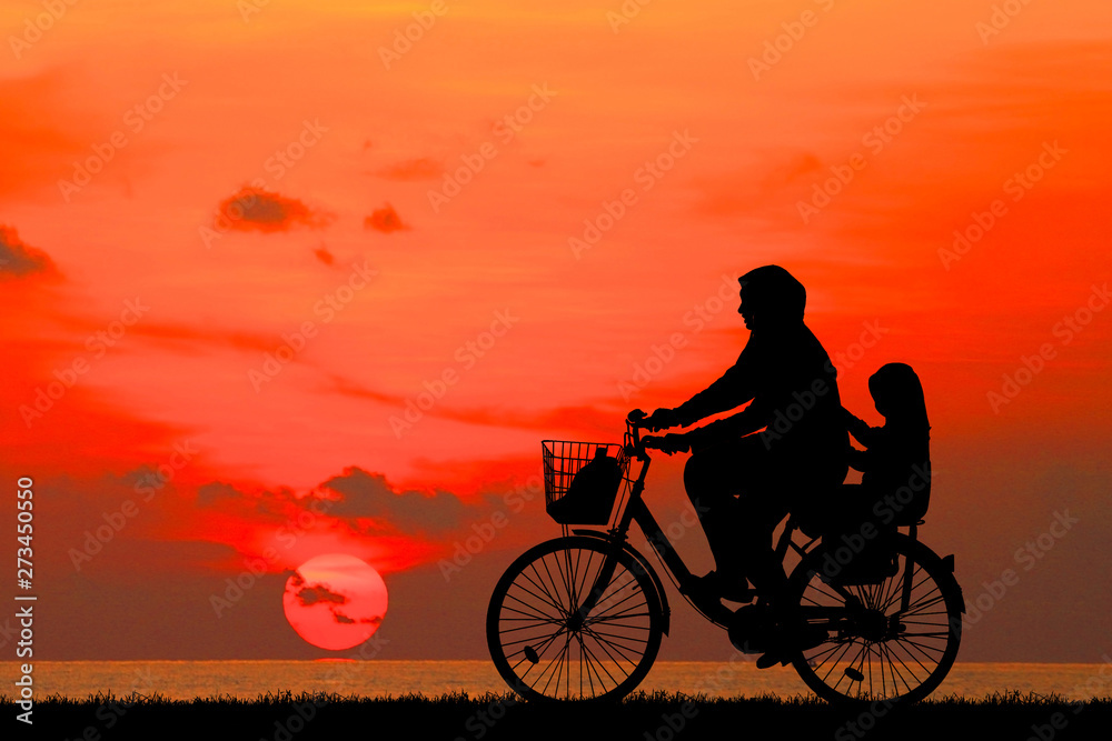  silhouette Mother and daughter ride bike on the beach