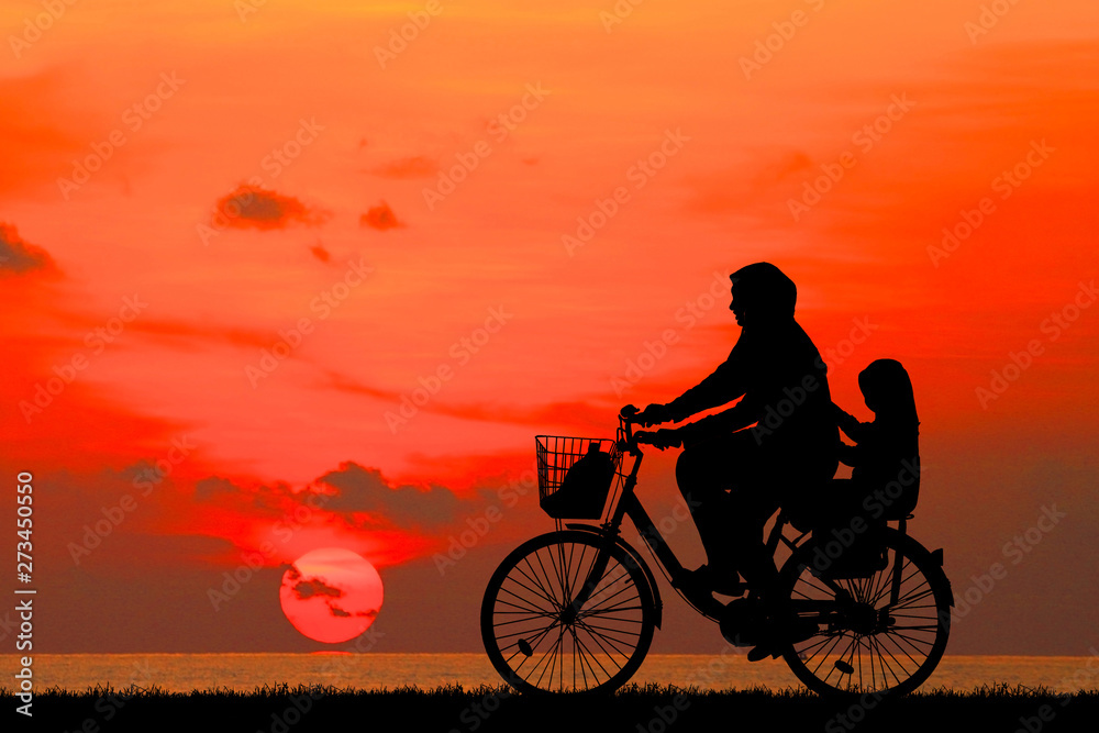 Fototapeta premium silhouette Mother and daughter ride bike on the beach