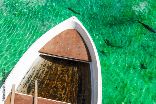 Small wooden boat in turquoise water in Lago Ghedina, an alpine lake in Cortina D'Ampezzo, Dolomites, Italy photo