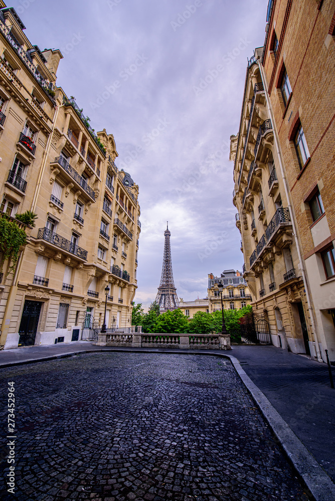 View of the Eiffel Tower between old tenements in a narrow Street