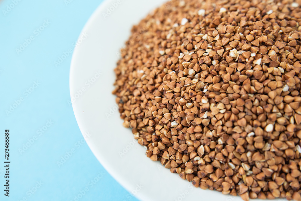 Plate with raw buckwheat on a blue background Plate with raw buckwheat on a blue background