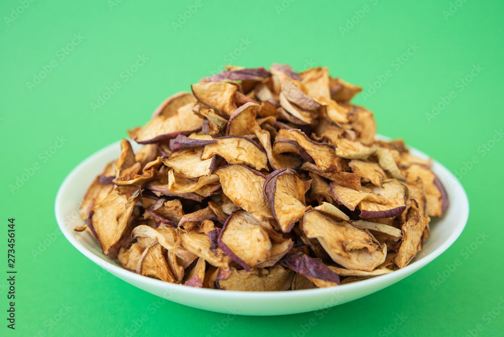 dried apples in white plate on green background dried apples in white plate on green background