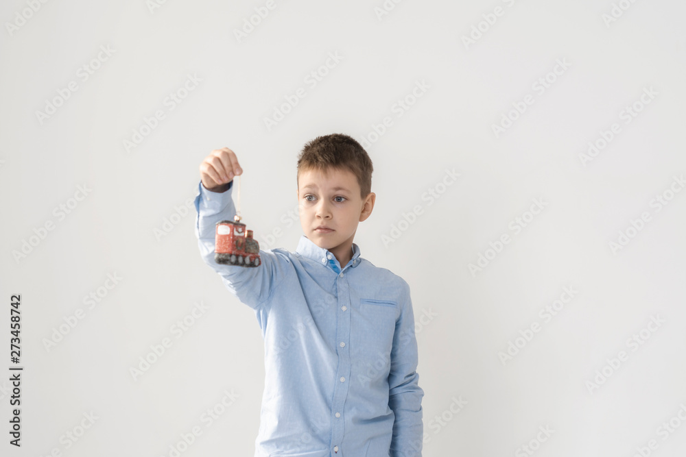 Boy with a surprised expression holding a beautiful Christmas toy on a white background in the Studio. Boy with a surprised expression holding a beautiful Christmas toy on a white background in the Studio.