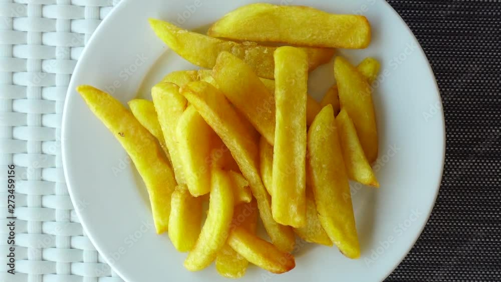 Fried potatoes on a plate rotates. View from above. The concept of junk food, fast food. Great for advertising or social networks. Fried potatoes on a plate rotates. View from above. The concept of junk food, fast food. Great for advertising or social networks.