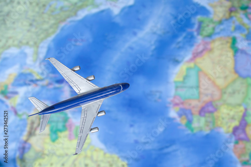 Toy plane over world map. Airplane flying through the Atlantic. Air trip, travel by plane, booking tickets, flight by aircraft concept