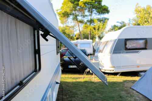 Open window of a camping trailer standing on a campsite in northern spain, near Sant Pere Pescador. White Mobil home omn the grass ground of the camping ground.