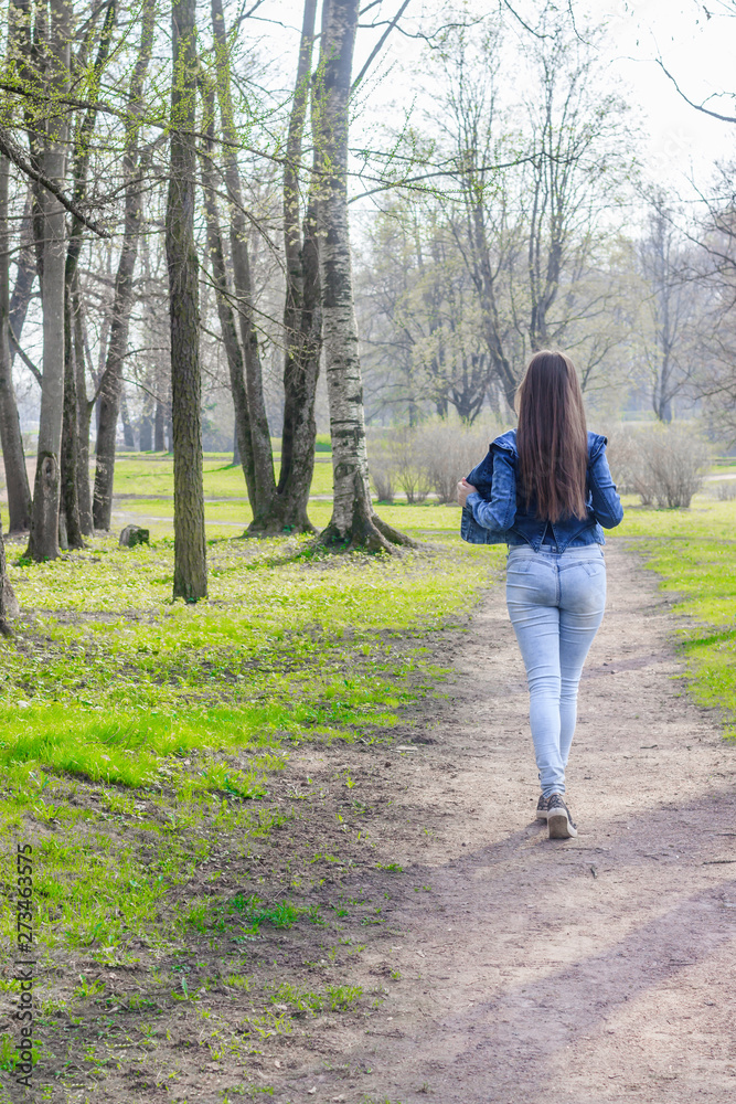 Girl in the spring in the park for a walk. The girl in the park. Walk in the park. in jeans and t-shirt.