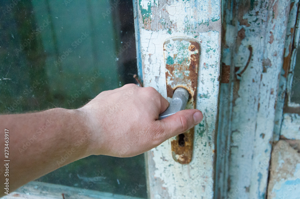old door knob. Paint peeled off the doors. Hand is taken by the handle old door knob. Paint peeled off the doors. Hand is taken by the handle