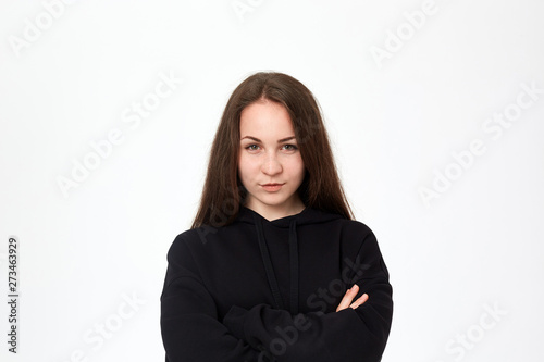 Portrait of a pretty young woman in a black sweatshirt standing infront of white background © ianachyrva
